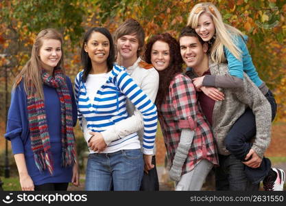 Group Of Six Teenage Friends Having Fun In Autumn Park