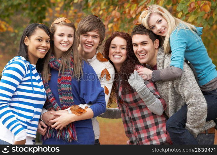 Group Of Six Teenage Friends Having Fun In Autumn Park