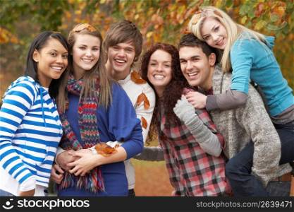 Group Of Six Teenage Friends Having Fun In Autumn Park