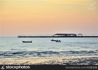 Group of small fishing boat on the sea with a bridge and sunset as background
