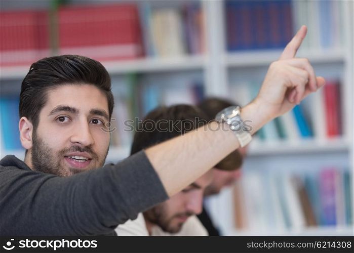 group of smart students raise hands up in school classroom on class