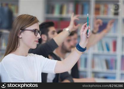 group of smart students raise hands up in school classroom on class