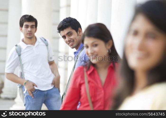 Group of smiling friends standing against columns