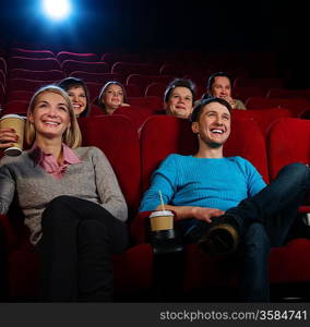 Group of smiling people watching movie in cinema