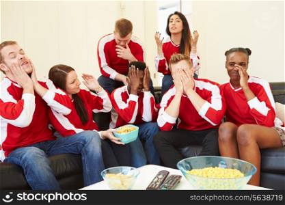Group Of Sports Fans Watching Game On TV At Home