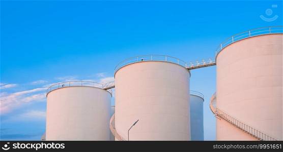 Group of storage fuel tanks in oil industrial manufacturing area against blue sky background, low angle and panoramic view