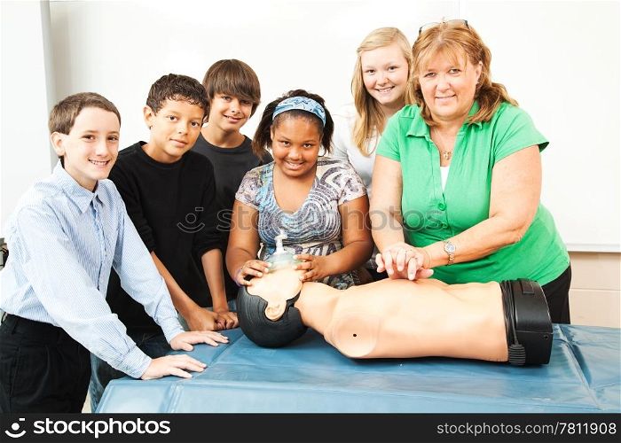 Group of students and their teacher, learning CPR in school.