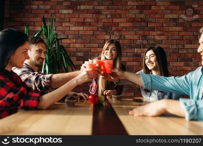 Group of students celebrate event. Youth with beverages at the table in college cafe, university party. Students celebrate event, university party