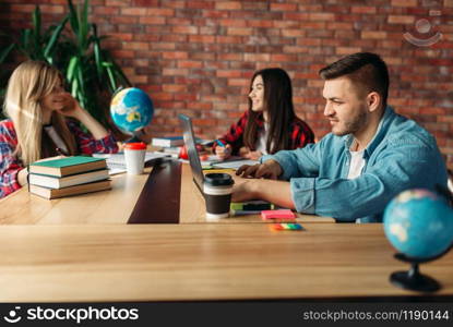 Group of students studying at the table together. People with laptop surfing information in internet, teamwork. Group of students studying at the table together