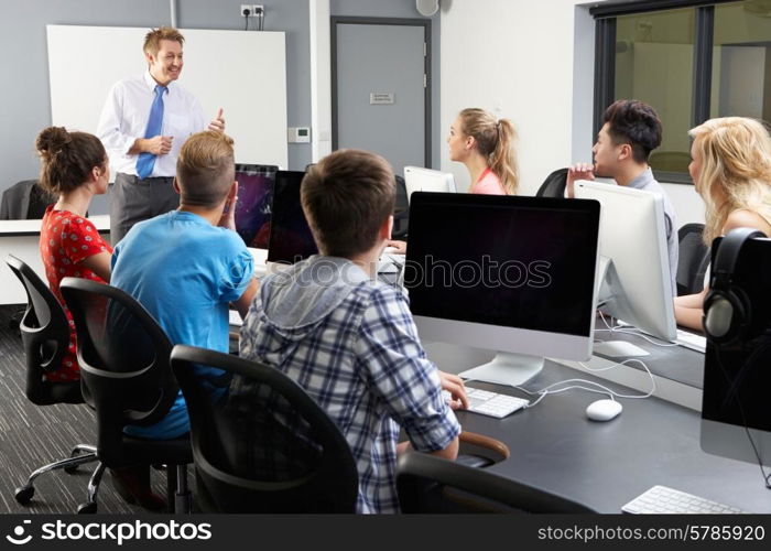 Group Of Students With Male Tutor In Computer Class