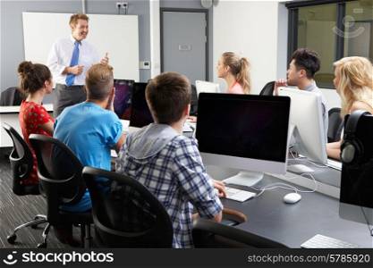 Group Of Students With Male Tutor In Computer Class