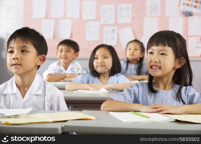 Group Of Students Working At Desks In Chinese School Classroom