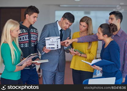 group of students working with teacher on wooden small house model