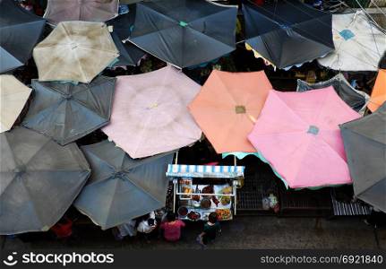 Group of sunshade from top view at outdoor farmers market, Ho Chi Minh city, Vietnam, woman at roast duck pushcart, amazing food counter from high view at morning