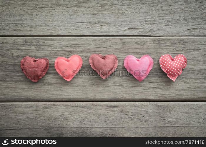 Group of sweet pink tone hearts handmade crafts from silk cloth place on wood background with vignette, , love and valentine&rsquo;s day symbol