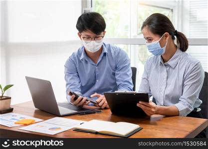 Group of Teamwork Asian business People Wearing Protective face Mask In Office During Pandemic coronavirus COVID-19, New Normal and Social distancing concept.