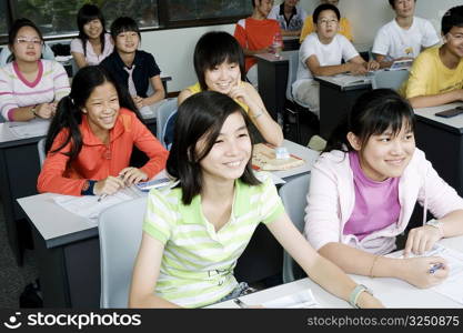 Group of teenage boys and teenage girls sitting in a classroom and smiling