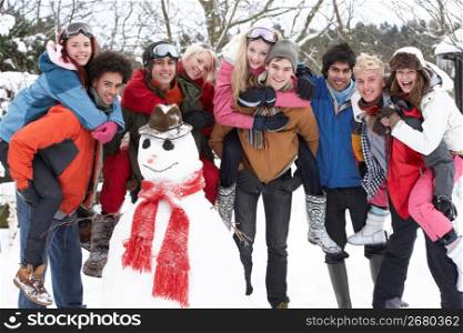 Group Of Teenage Friends Building Snowman In Garden