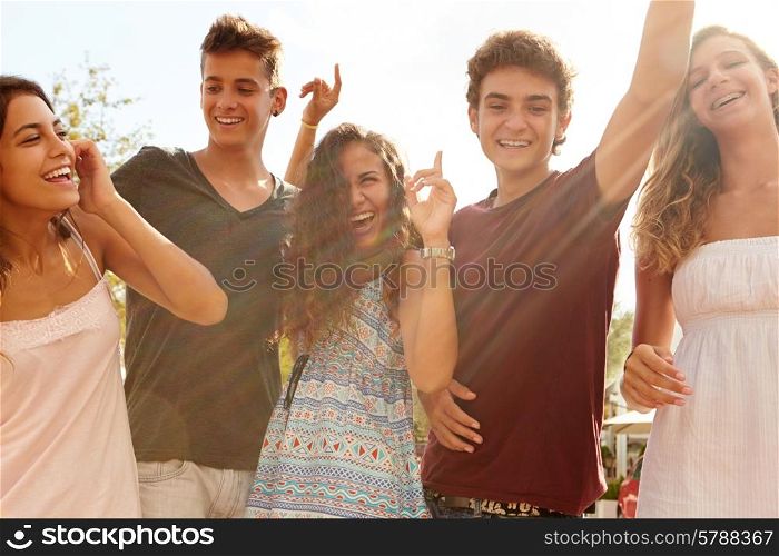 Group Of Teenage Friends Dancing Outdoors Against Sun