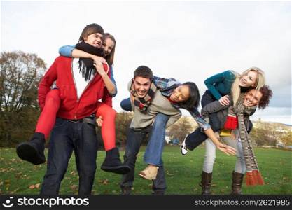 Group Of Teenage Friends Having Piggyback Rides In Autumn Landscape