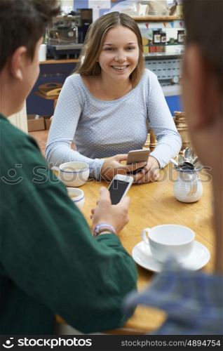 Group Of Teenage Friends Meeting In Cafe And Using Mobile Phones