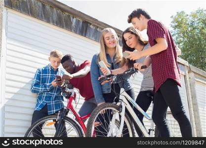 Group Of Teenage Friends On Bikes Looking At Mobile Phones