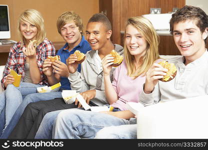 Group Of Teenage Friends Sitting On Sofa At Home Eating Fast Food