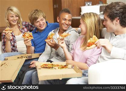 Group Of Teenage Friends Sitting On Sofa At Home Eating Pizza