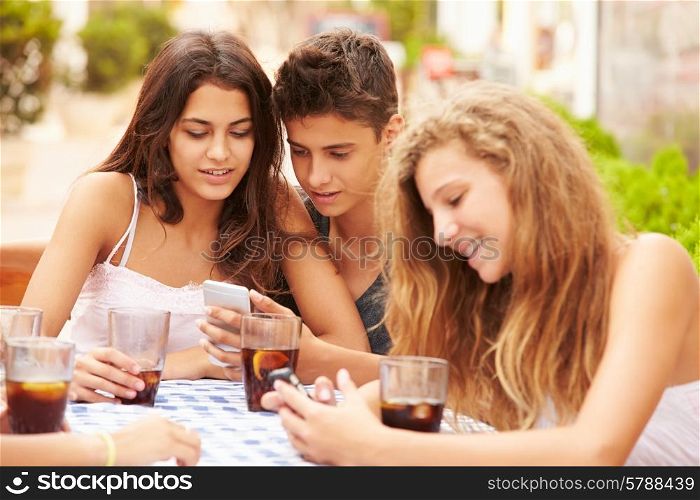 Group Of Teenage Friends Using Mobile Phone Sitting At Caf?