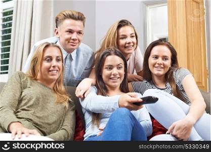 Group Of Teenage Friends Watching Television At Home