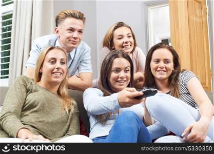 Group Of Teenage Friends Watching Television At Home