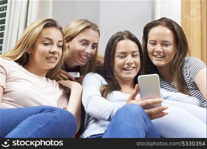 Group Of Teenage Girls Reading Text Message On Mobile Phone