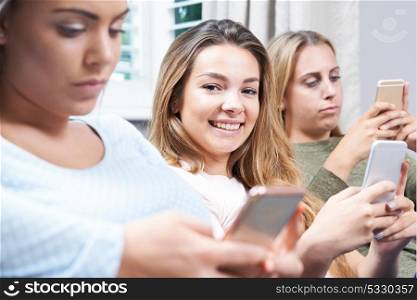 Group Of Teenage Girls Using Mobile Phones At Home