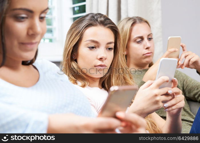 Group Of Teenage Girls Using Mobile Phones At Home