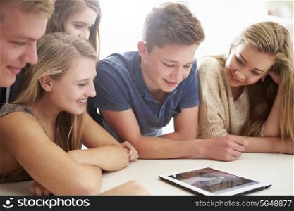 Group Of Teenagers Gathered Around Digital Tablet Together