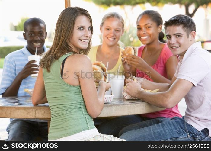 Group Of Teenagers Sitting Outdoors Eating Fast Food