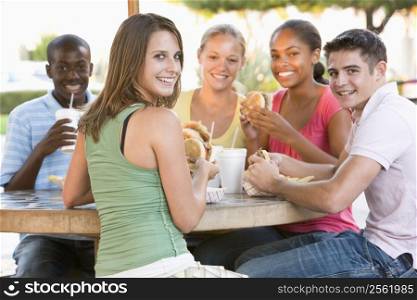 Group Of Teenagers Sitting Outdoors Eating Fast Food