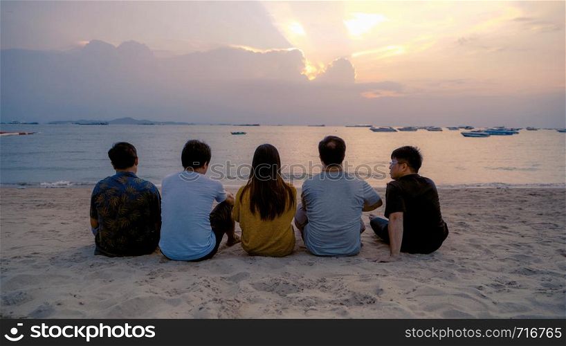 Group of Thai people, Asian friends, clanging bottles of beer together and celebrating on holiday in party at the beach or sea in summer at sunset time
