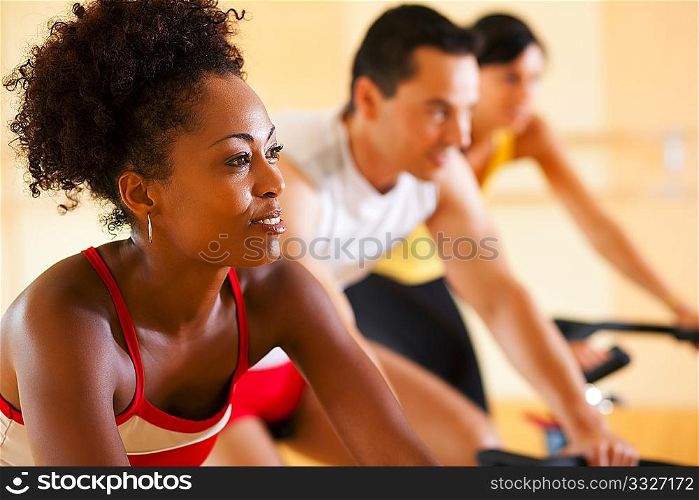 Group of three people - presumably friends - spinning in the gym, , exercising for their legs and cardio training