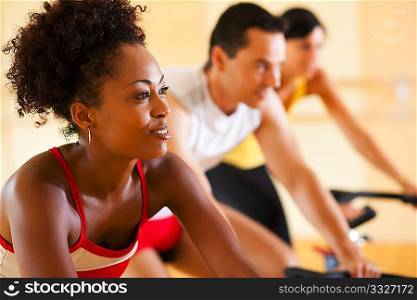 Group of three people - presumably friends - spinning in the gym, , exercising for their legs and cardio training