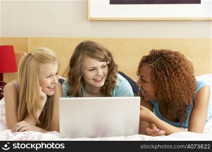 Group Of Three Teenage Girls Using Laptop In Bedroom