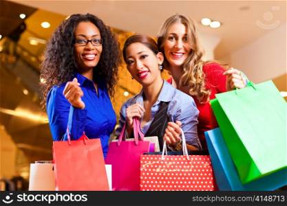 Group of three women - white, black and Asian - shopping downtown in a mall