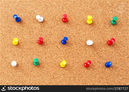 Group of thumbtacks pinned on corkboard