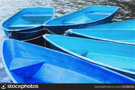Group of tied blue and turquoise recreation rowing boats on the water closeup. Soft selective focus.. Blue Recreation Boats