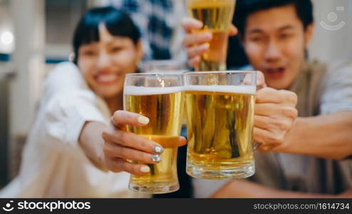 Group of tourist young Asia people using mobile phone greeting friends on remote video call, drink alcohol beer and having hangout party in night cafe. Traveler backpacker travel in Bangkok, Thailand.