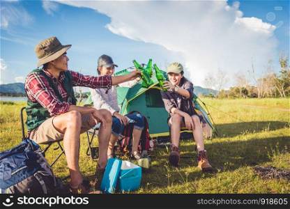 Group of travelers camping and doing picnic in meadow with tent foreground. Mountain and lake background. People and lifestyles concept. Outdoors activity and leisure theme. Backpacker and Hiker theme