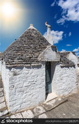 Group of Trulli with symbols, traditional old houses and old stone wall in Puglia, Italy