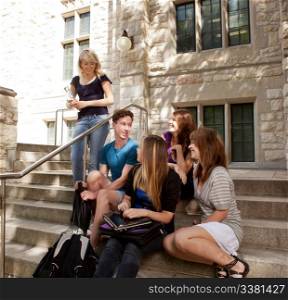Group of university or college students sitting on steps, visiting and having fun