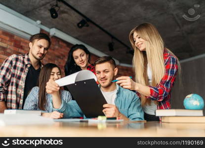 Group of university students looking on laptop together. People with computer search information in internet, teamwork, joint project