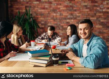 Group of university students sitting at the table together. People with laptop search information in internet. Group of university students sitting at the table
